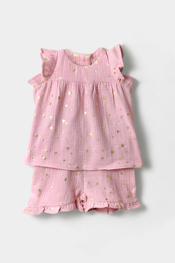 Pink children's outfit with ruffled top and shorts on a light gray background