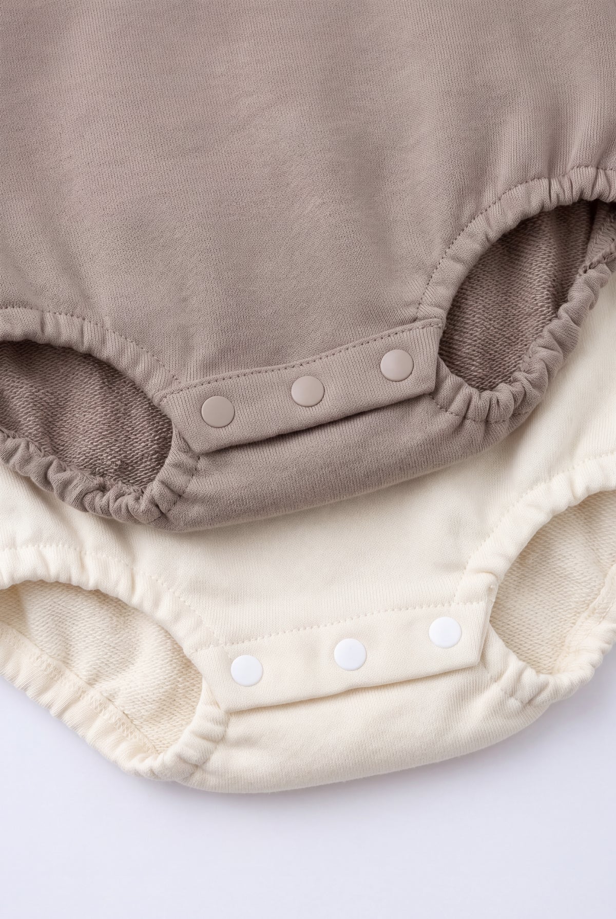 PTex Fashion baby bodysuits close-up showing three-snap crotch closure and elasticated leg openings in mocha and cream