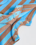 Close-up of metal snap fasteners along the inner leg of a blue and brown striped baby romper, showing the easy-change nappy opening.