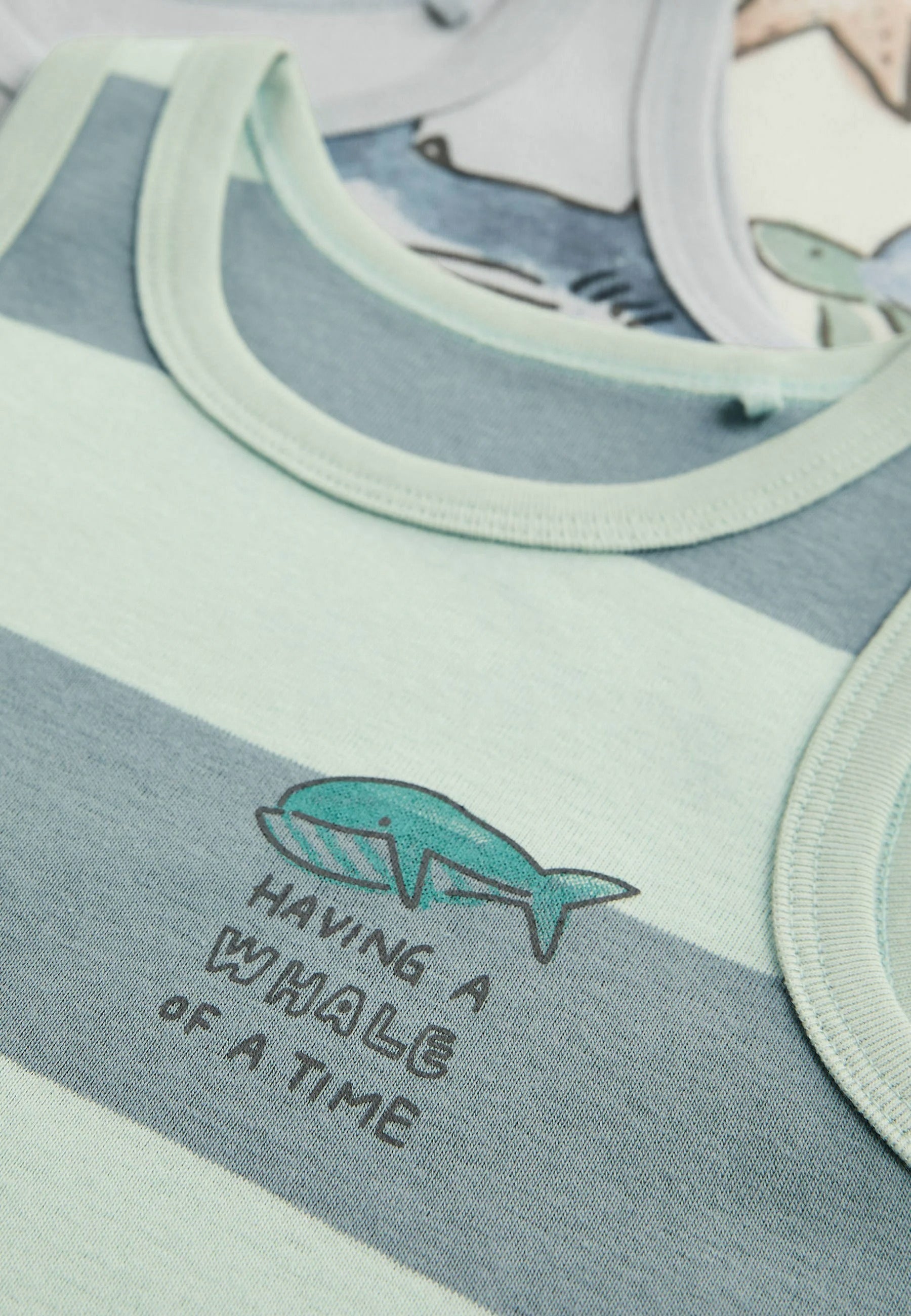 Children's tank tops with whale design and text 'Having a whale of a time' on a blue and green background.