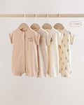 Front view of four baby rompers hanging on wooden hangers, showing the snap-front openings and short sleeves in a soft neutral colour palette.