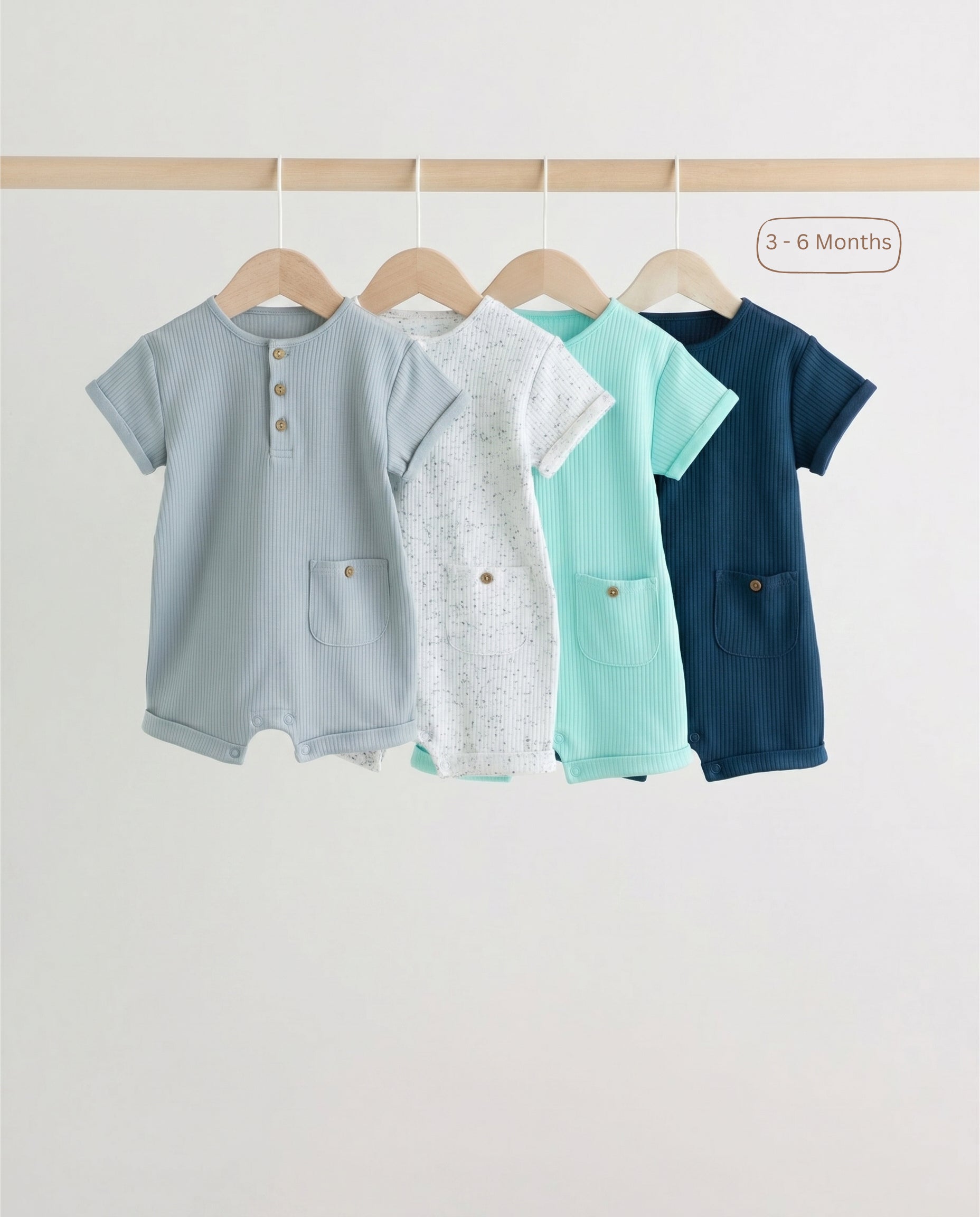 Close-up of ribbed cotton baby romper fabric in speckled ivory, mint and navy showing soft knit texture