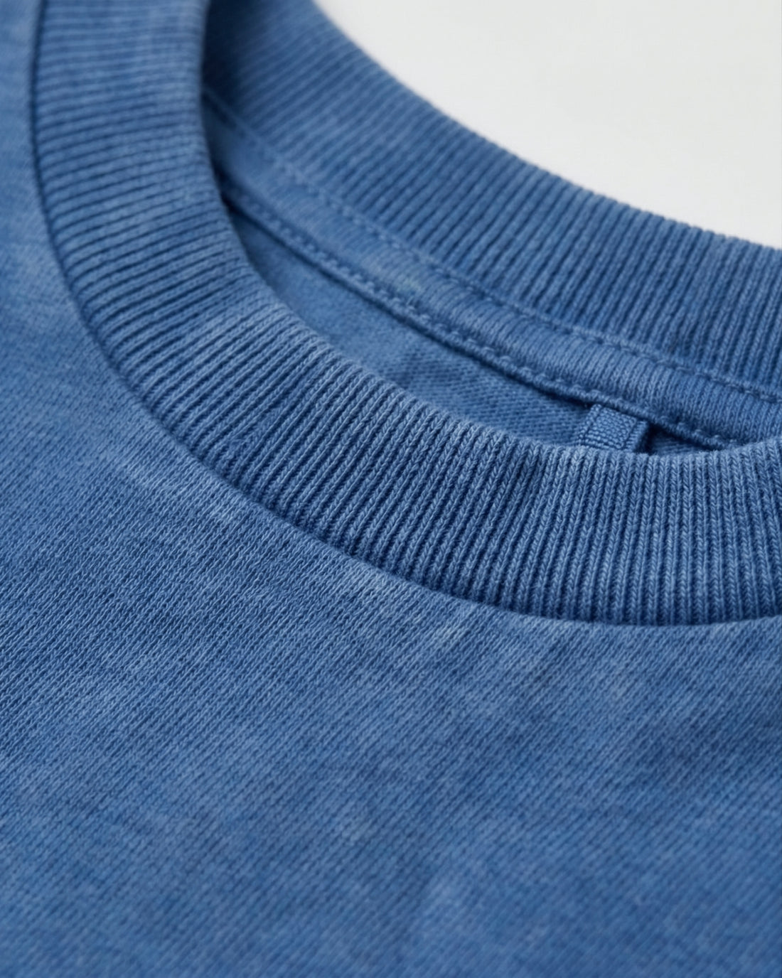 Flat lay of a boy's blue acid wash crew neck T-shirt with short sleeves and a relaxed fit, displayed on a light grey background.