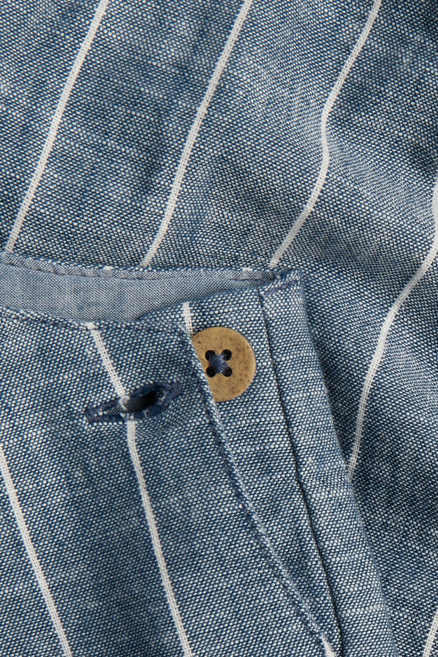 Close-up of PTex Fashion striped chambray dungaree fabric and wooden button detail