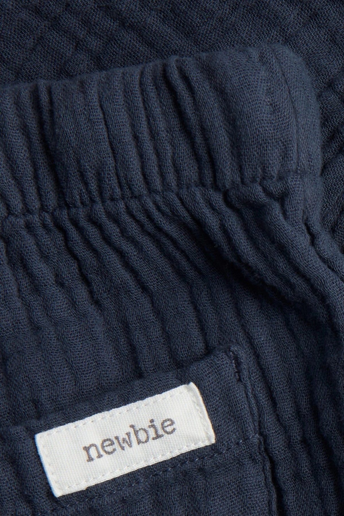 Close-up of elasticated waist and back patch pocket on navy blue baby muslin trousers — PTex Fashion