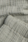 Close-up of crinkle cotton muslin fabric texture and elasticated cuff on sage green baby trousers — PTex Fashion