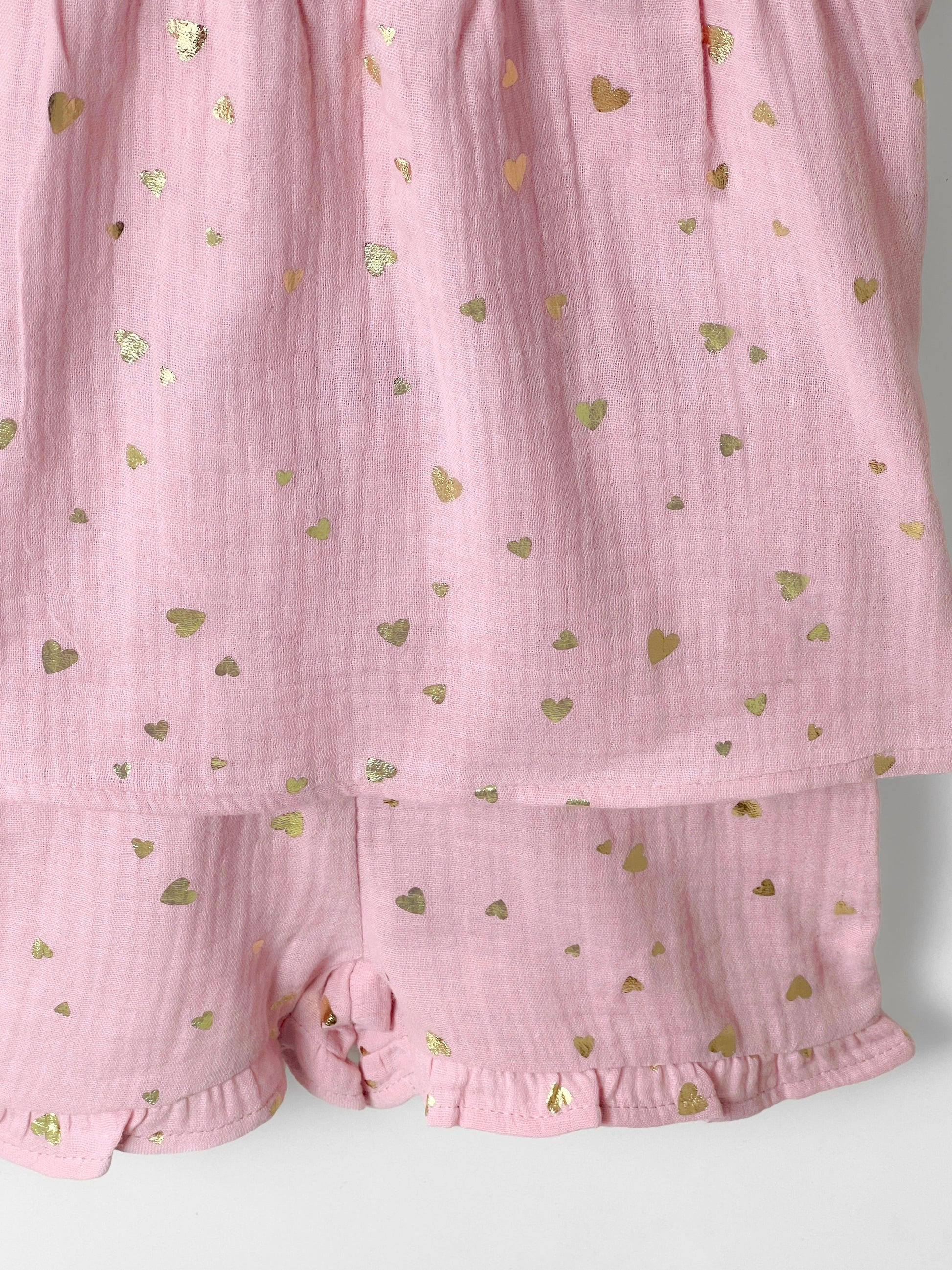 Pink baby muslin dress with gold heart patterns on a white background