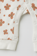 Baby romper with floral pattern and white trim on a light background