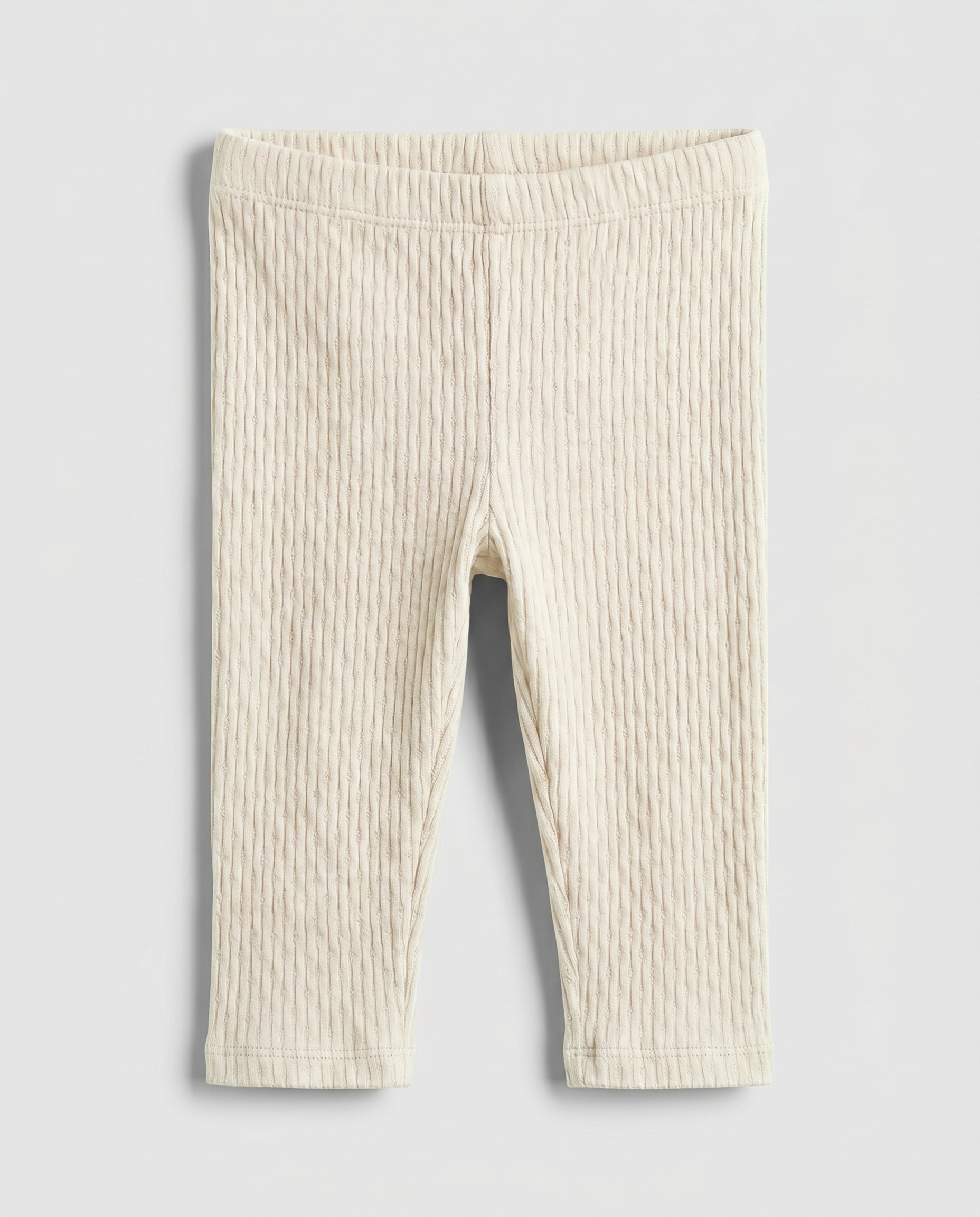Baby girls' cream cable-knit leggings with wide elasticated waistband, flat lay