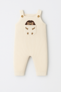 Beige baby romper with embroidered face on a white background