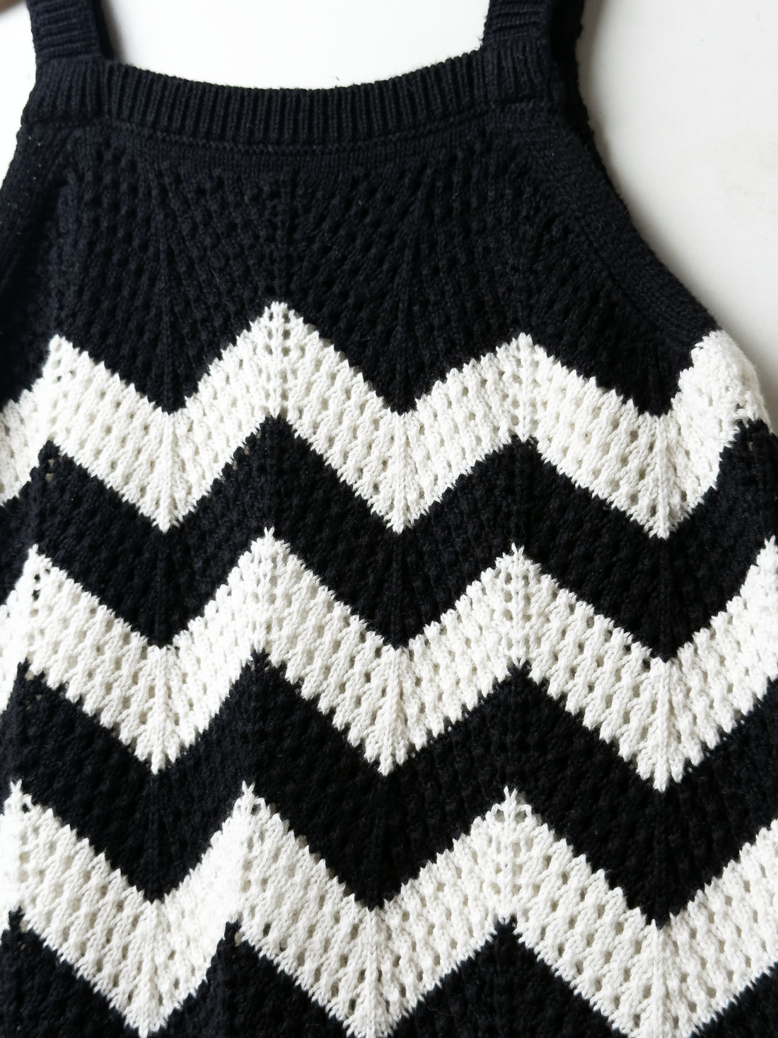 Black and white chevron patterned sweater on a plain background