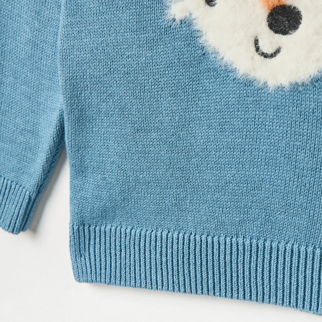 Blue sweater with fox face design on a light gray background