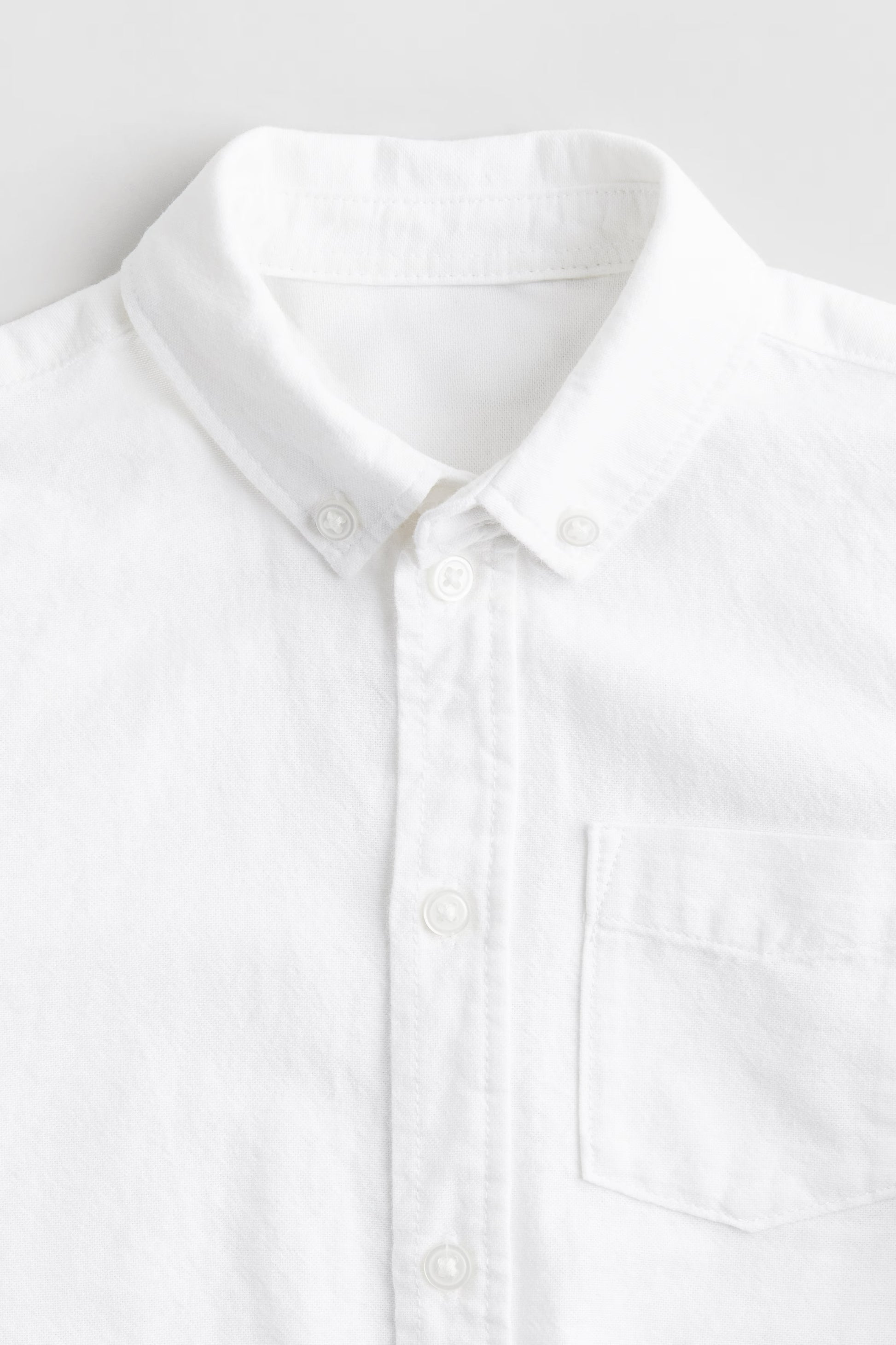Close-up of a white shirt with a collar on a light gray background