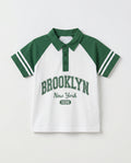 Boys' green and white raglan polo shirt with Brooklyn varsity print and striped sleeve detail, front view