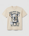 
Boys' cream-colored short-sleeve cotton t-shirt laid flat, featuring a graphic print of a cartoon koala wearing headphones and holding a gaming controller, with arched text reading 