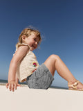 Child sitting on a sandy beach with a clear blue sky