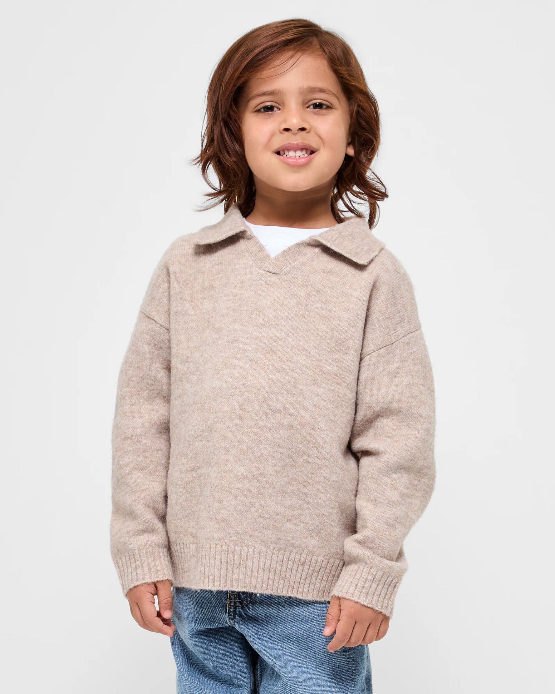 Child wearing a beige sweater with a collar on a white background