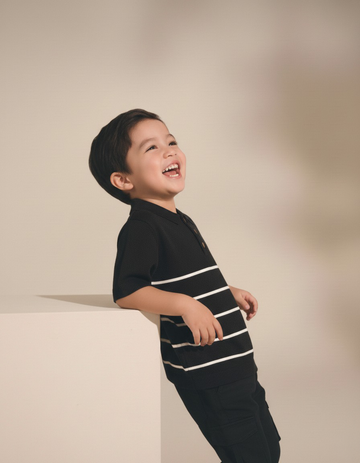 Child wearing a black and white striped shirt against a beige background
