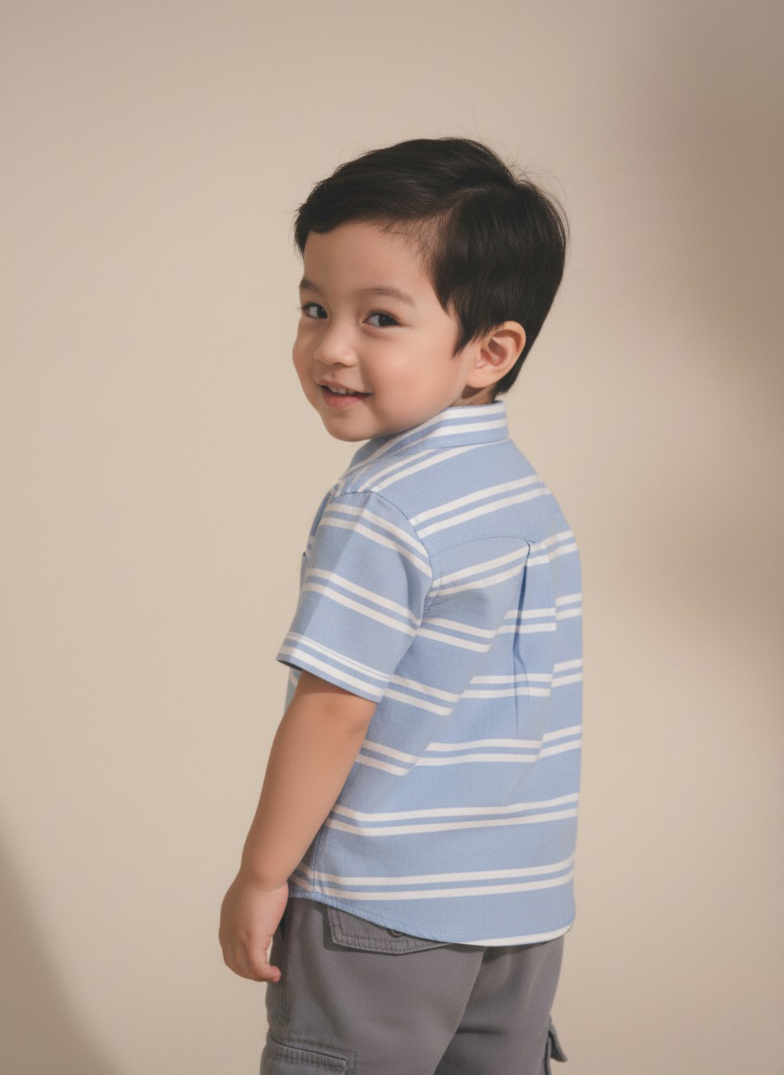 Child wearing a blue striped shirt against a beige background