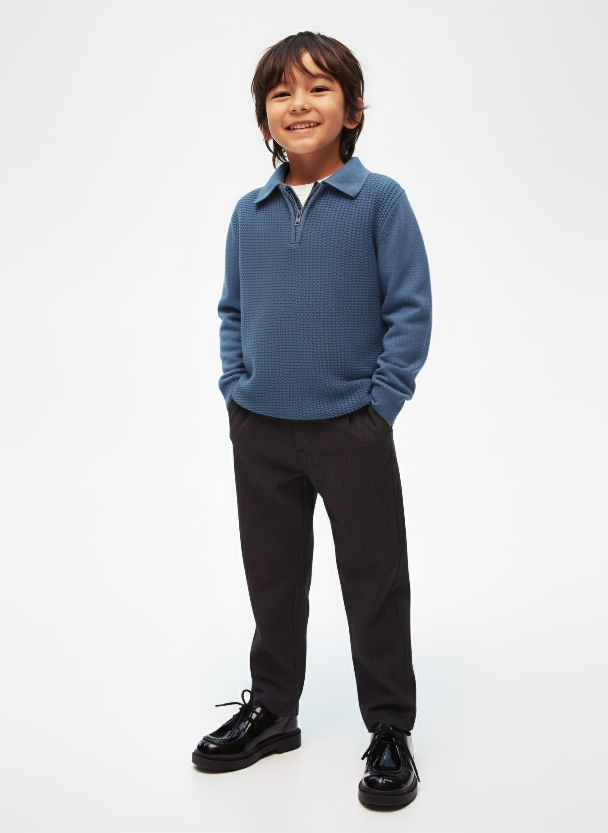 Child wearing a blue sweater and black pants on a white background