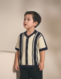 Child wearing a navy and cream striped shirt against a beige background