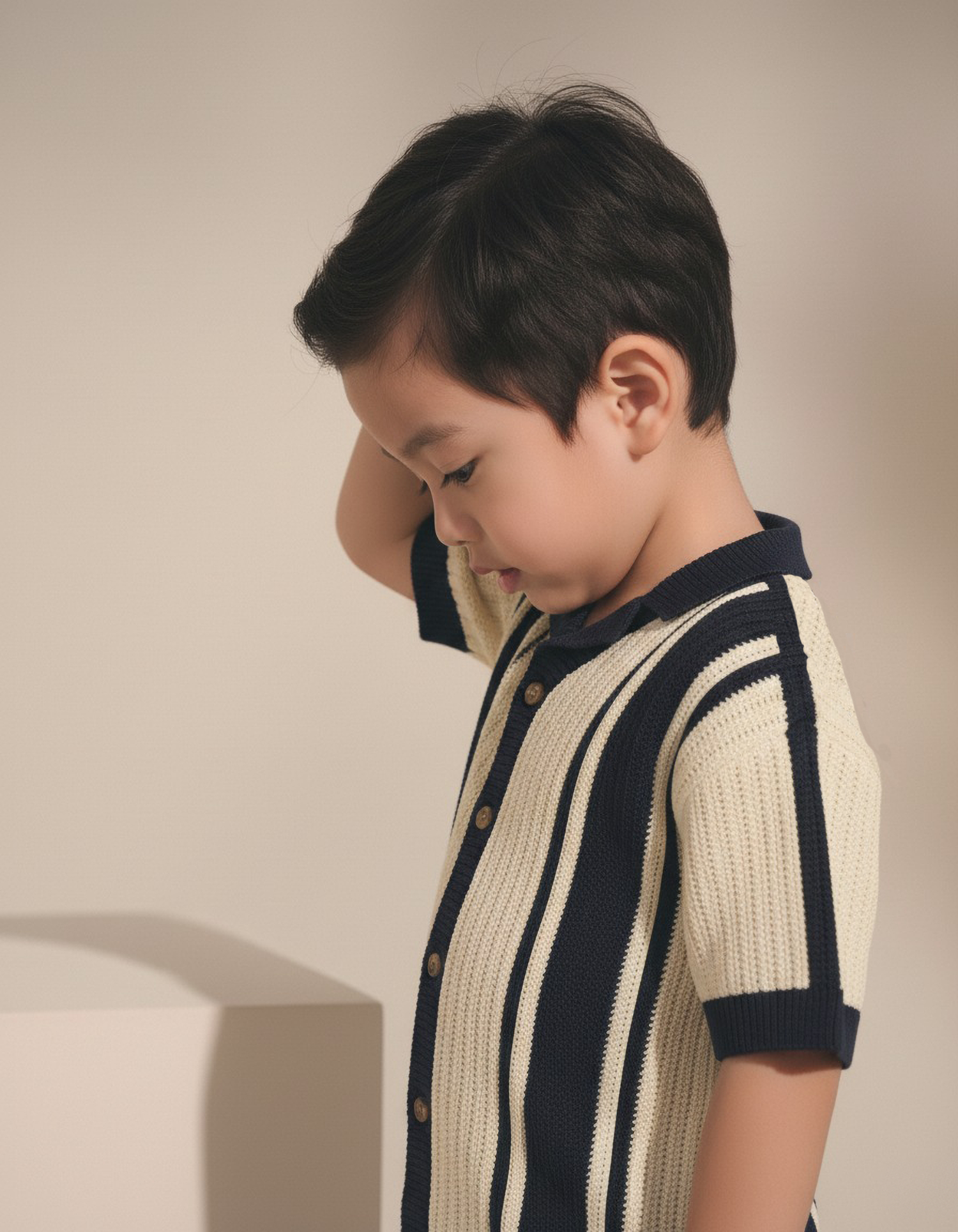 Child wearing a striped sweater against a neutral background