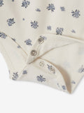 Close-up of a baby outfit with floral pattern and buttons on a white background