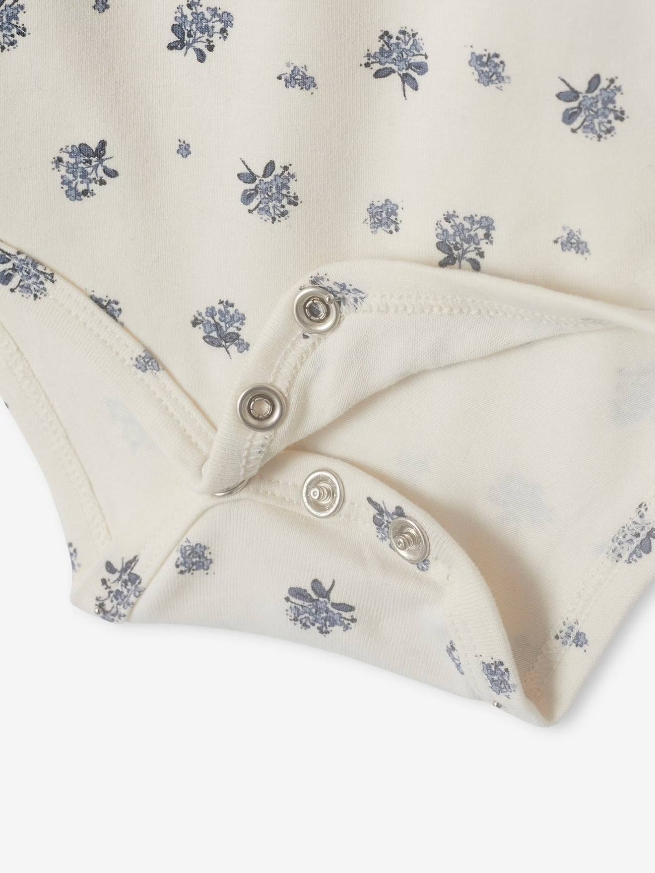 Close-up of a baby outfit with floral pattern and buttons on a white background