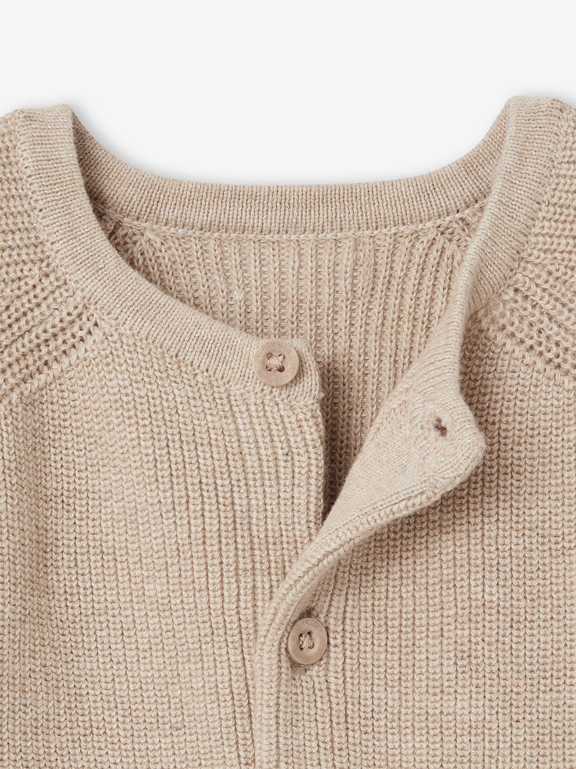 Close-up of a beige knitted cardigan with buttons on a light background