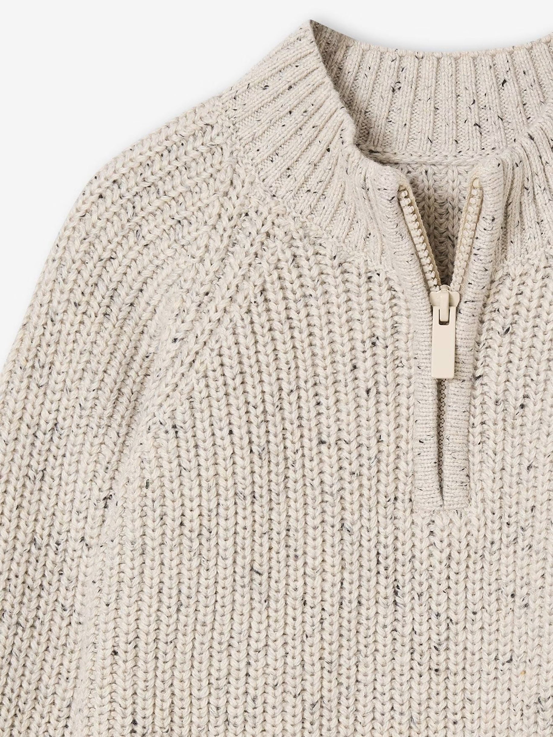 Close-up of a beige knitted sweater with a zipper on a white background