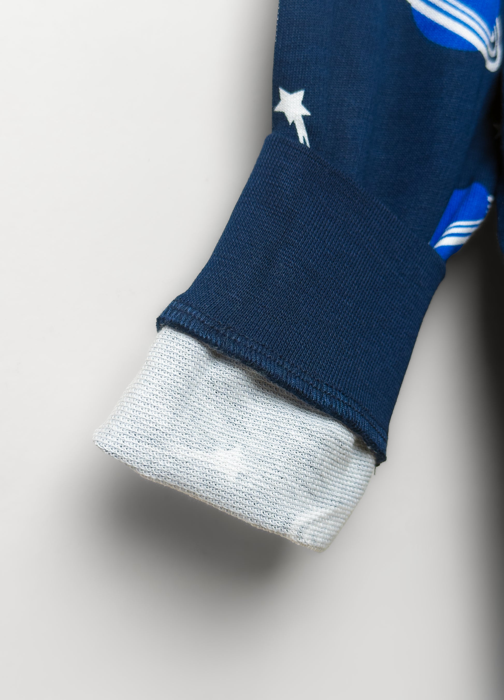 Close-up of a blue sleeve with white star and gray cuffs on a light gray background