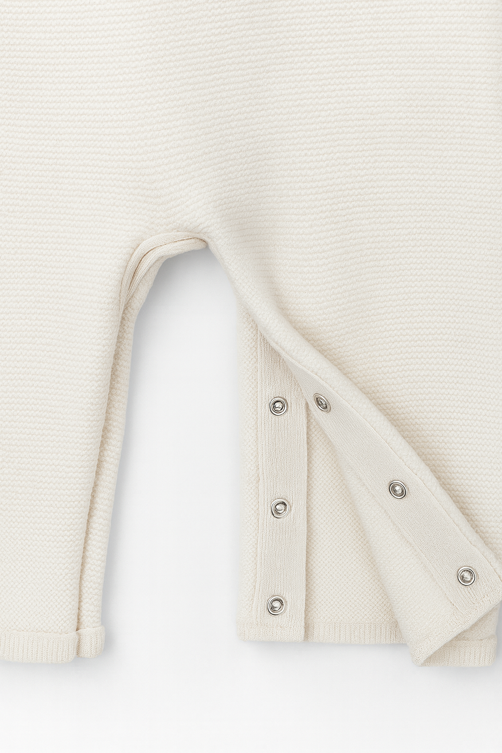 White ribbed knit overalls with button details on a light gray background