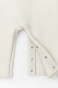 Close-up of a cream-colored garment with button details on a white background