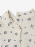 Close-up of a cream-colored garment with small floral patterns on a white background
