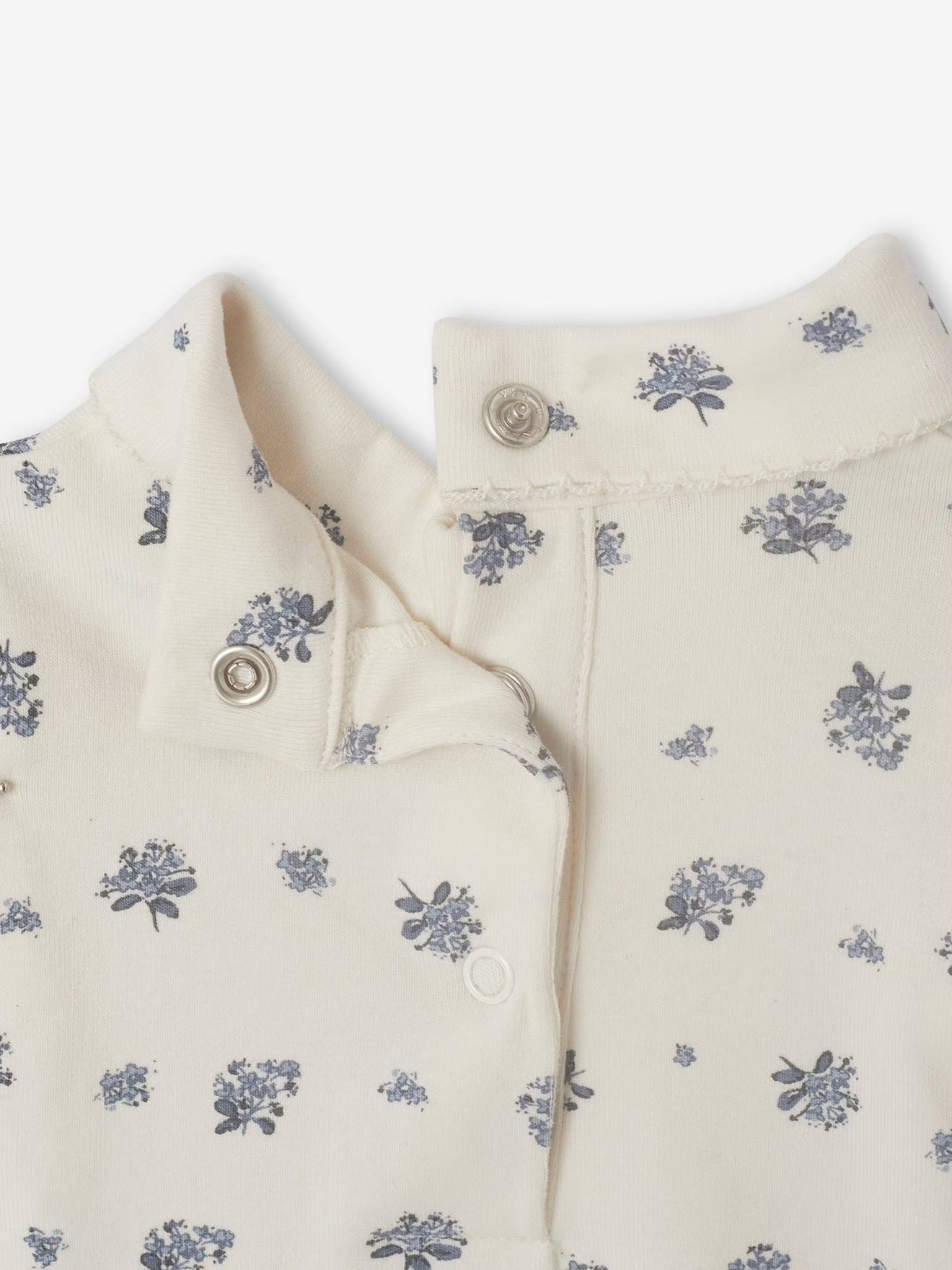 Close-up of a cream-colored garment with small floral patterns on a white background