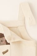 Close-up of a cream-colored knit garment with a small animal design on a light background