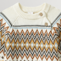 Close-up of a cream-colored sweater with a patterned design on a light gray background