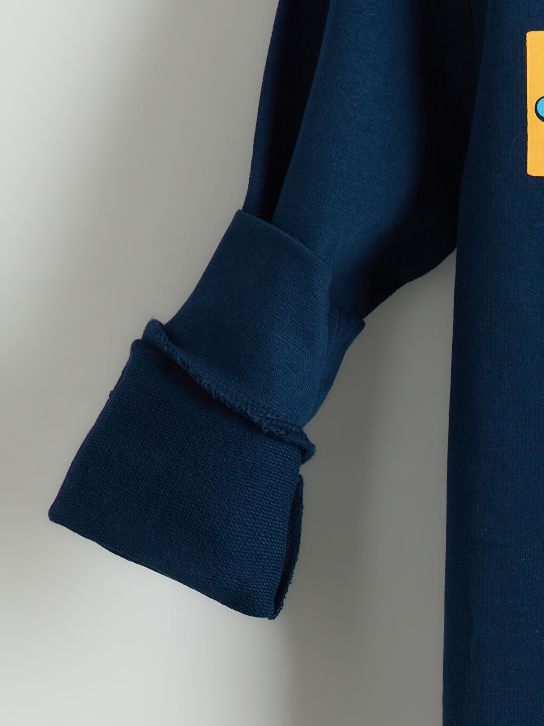 Close-up of a navy blue sleeve with a yellow patch on a light gray background