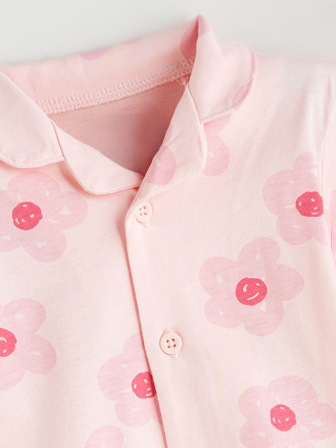 Pink shirt with red floral patterns on a light gray background