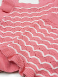 Close-up of a pink knitted garment with white ribbing on a white background