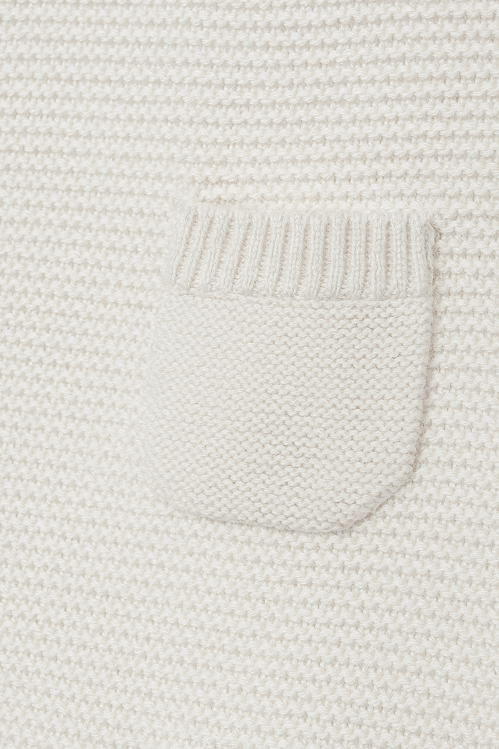 Close-up of a textured white fabric with a pocket detail