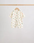 Cream all-over print baby romper with scattered caterpillar and fruit motifs, wooden button front placket, on wooden hanger

