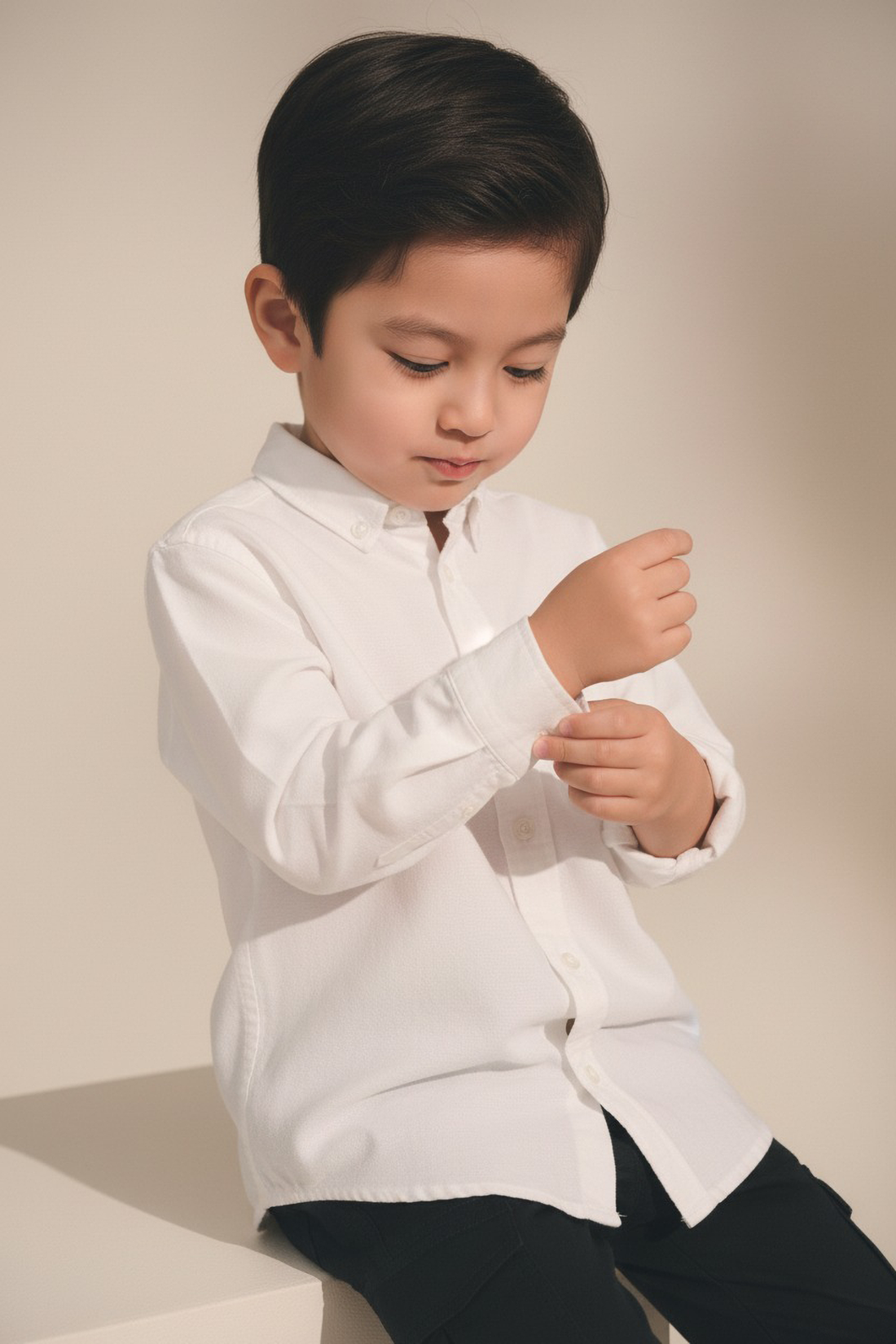 Child wearing a white shirt and black pants against a plain background