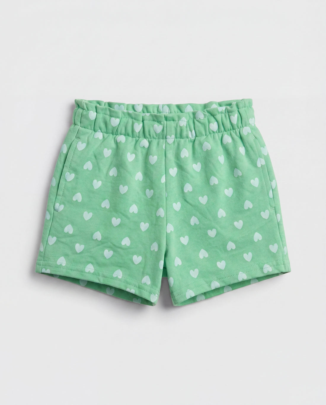 Front flat-lay view of girl's green short pant with all-over scattered white heart print and ruched paperbag elasticated waistband
