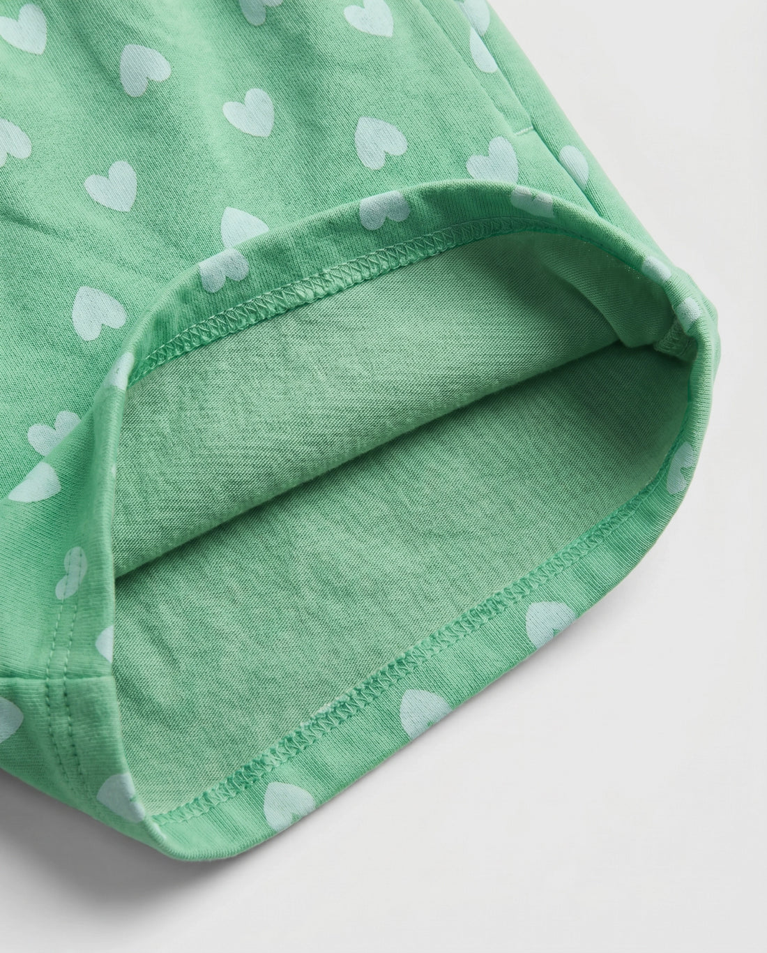 Front flat-lay view of girl's green short pant with all-over scattered white heart print and ruched paperbag elasticated waistband