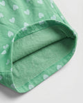 Close-up of green heart print cotton fabric showing matching soft green cotton inner lining and overlock stitch hem detail of girl's short pant