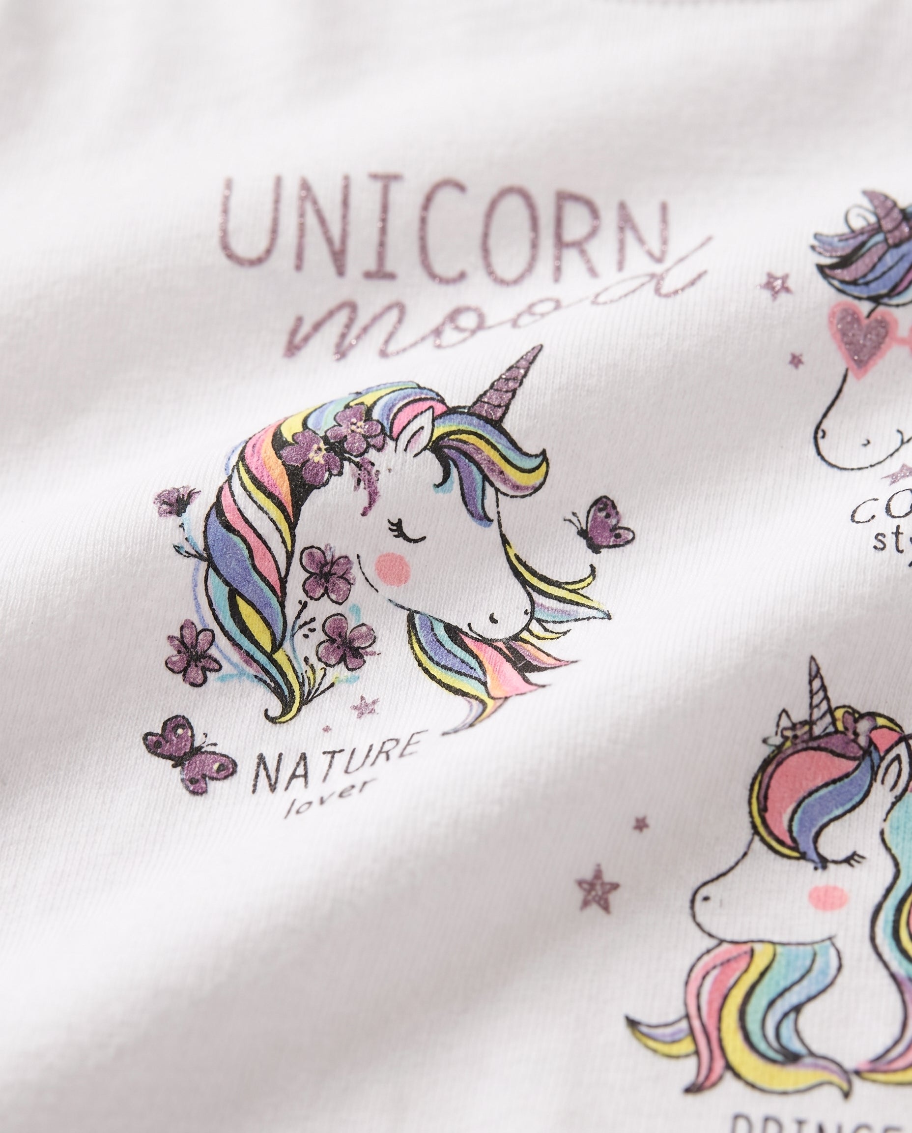 Close-up of rainbow-maned unicorn with flowers and butterflies glitter print on white girls' cotton tee