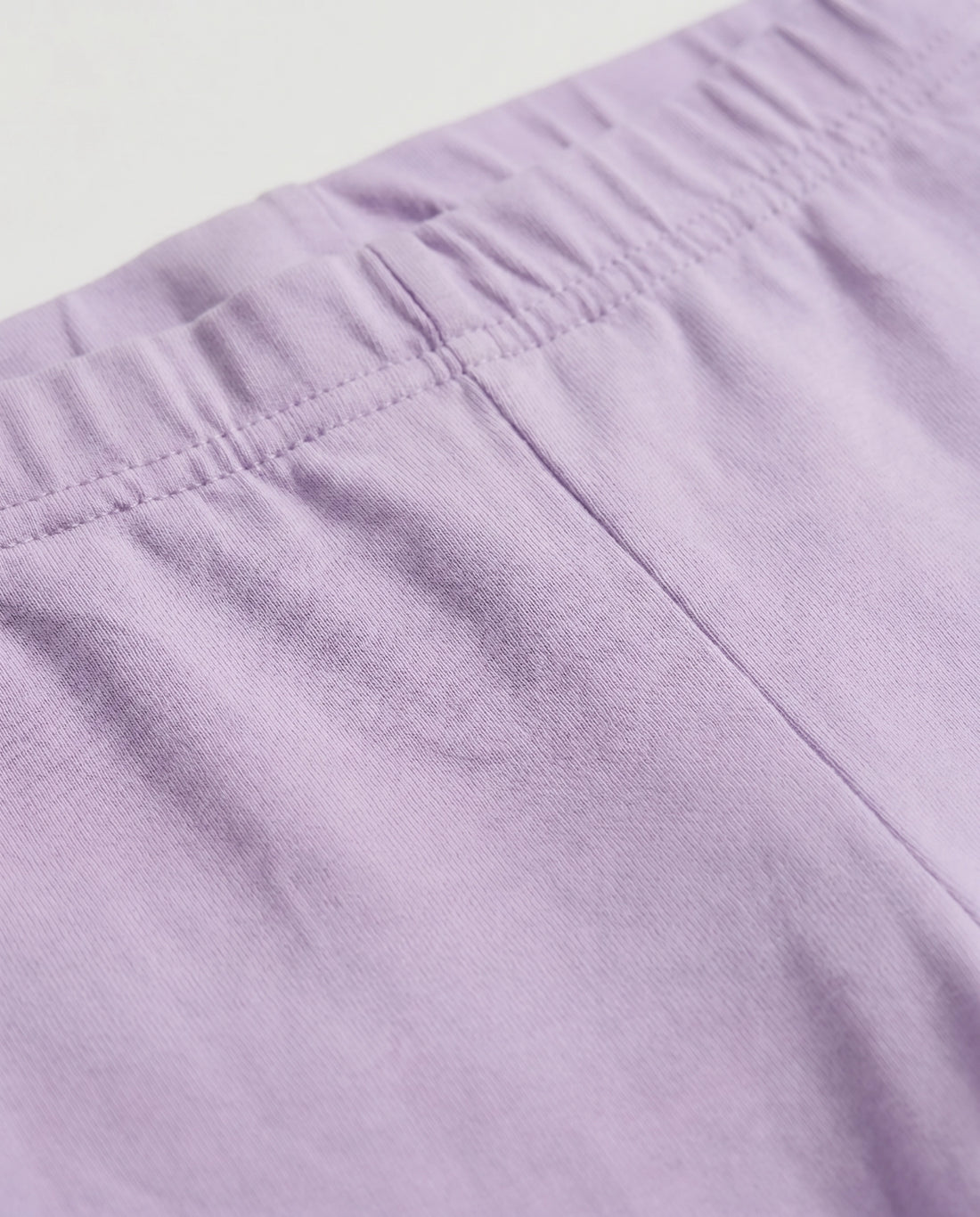 Full-length girls' slim-fit leggings in baby purple, plain design with elasticated waistband, laid flat on a light grey background.