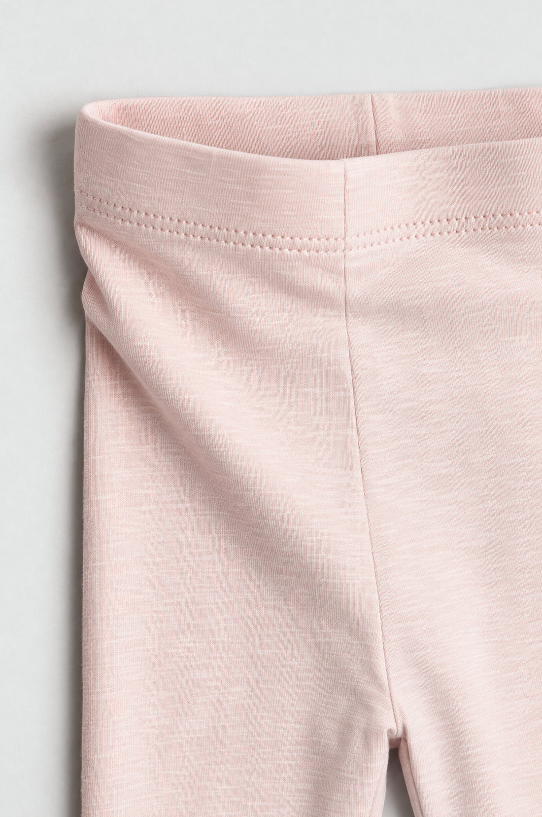 Girls’ blush pink heathered leggings with elastic waistband and slim tapered legs.