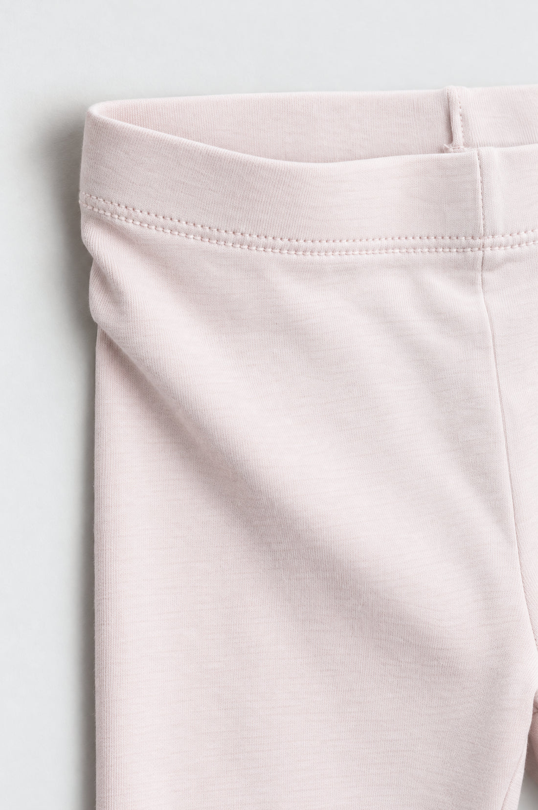 Girls’ pale blush pink leggings with elastic waistband, slim tapered legs and neatly stitched ankle hems.